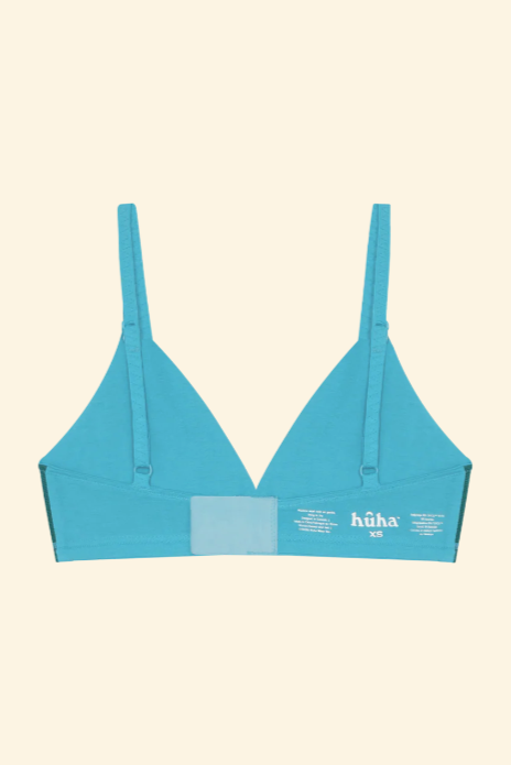 Blue bikini top with 'huka' branding on a beige background