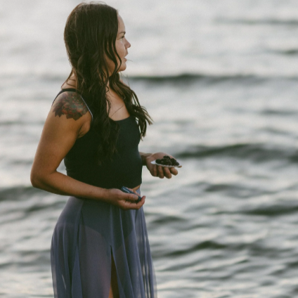 Woman standing by a body of water holding a small object