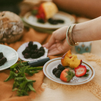 Person at a picnic table with food and a blurred background