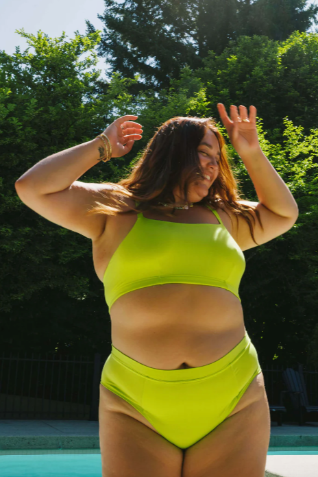 Person wearing a bright green bikini set with trees and pool in the background