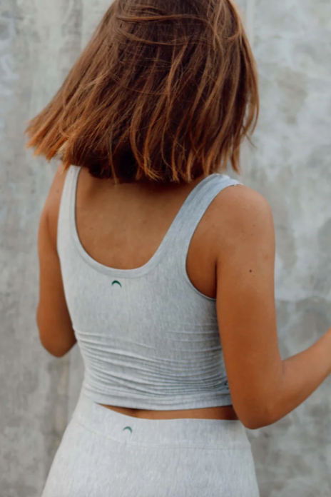Person wearing a gray tank top against a textured wall