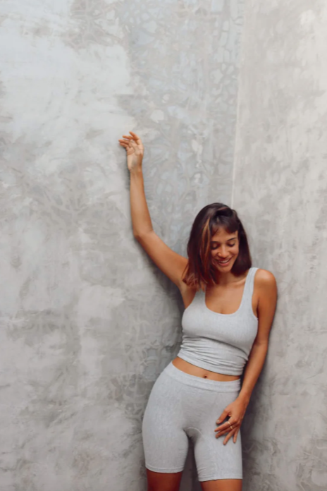 Woman in gray athletic wear posing against a textured gray wall
