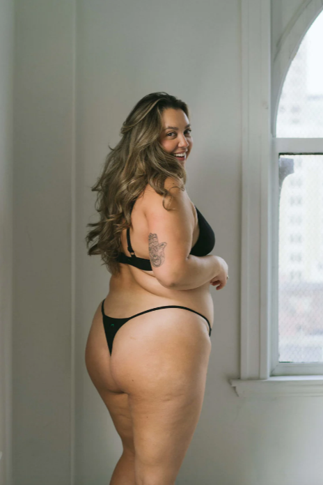 Woman wearing black lingerie standing in a room with a window in the background