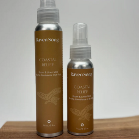 Two bottles of Raven Song Coastal Relief spray on a wooden surface with a gray background.