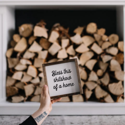 Stack of firewood in a fireplace with a framed sign held in front