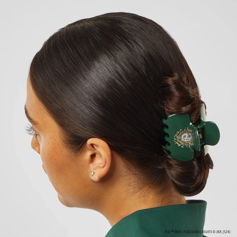 Person with a green hair clip in their hair against a gray background