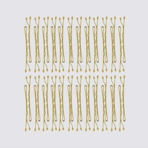 Multiple gold hair pins arranged in rows on a light gray background