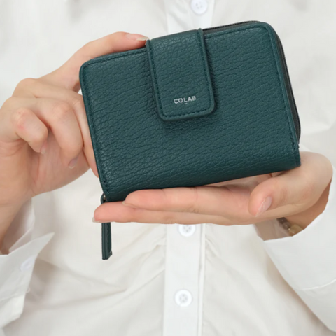 Green wallet held in a hand with a white background