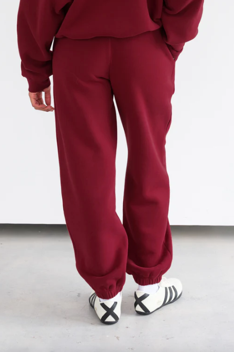 Person wearing a red tracksuit with white sneakers on a light gray floor.