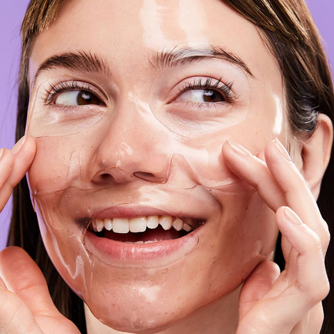 Woman applying a skincare product to her face with a purple background