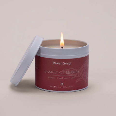 Candle in a red container labeled 'Raven Song Basket of Berries' on a beige background