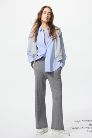 Woman wearing a light blue shirt, gray pants, and white sneakers on a white background