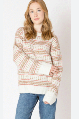 Woman wearing a patterned sweater and jeans on a plain background
