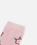 A close-up of a light pink knit sock with a repeating pattern of red and white flowers with green leaves, shown against a plain light gray background.