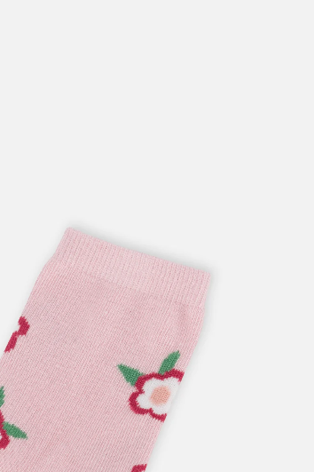 A close-up of a light pink knit sock with a repeating pattern of red and white flowers with green leaves, shown against a plain light gray background.