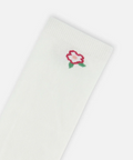 A close-up of a white ribbed sock featuring a small embroidered rose motif in red, pink, and green near the cuff, set against a clean white background.