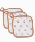 Three white baby bibs with gold patterns on a white background