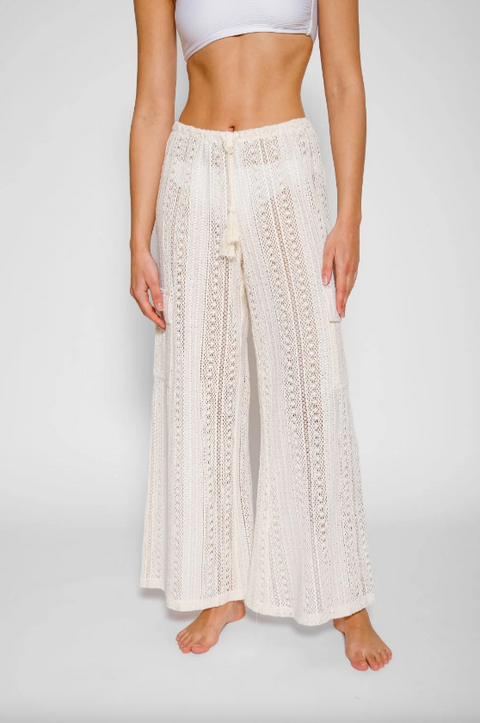 Person wearing white lace pants on a plain background