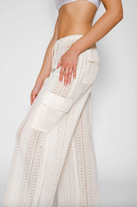 White embroidered pants being worn on a plain background
