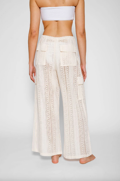 Person wearing white lace pants and a matching top on a plain background