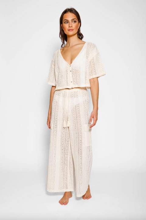 Woman wearing a white lace outfit on a plain background