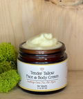 A jar of Tender Tallow Face & Body Cream placed on a wooden surface, with a label that includes the product name and a brief description.