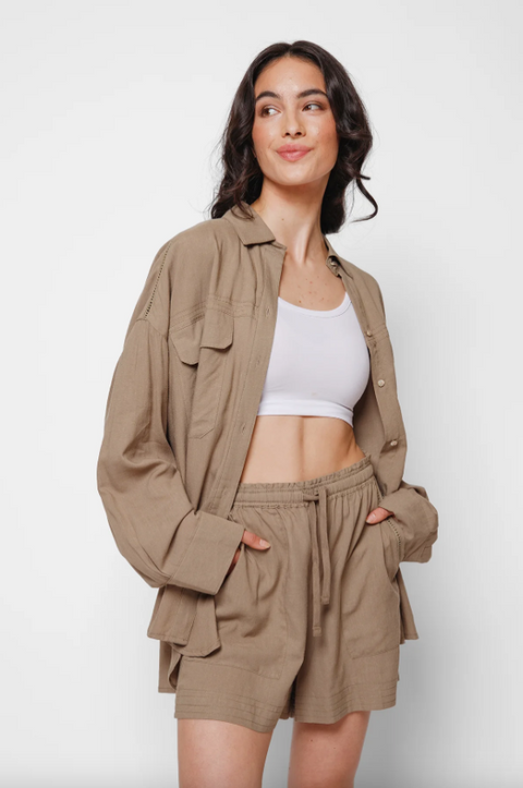 Woman wearing a beige jacket and shorts set with a white top on a white background