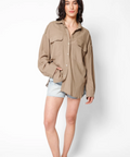Woman wearing a beige jacket and denim shorts on a white background