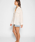 Woman wearing a light-colored shirt and denim shorts on a white background