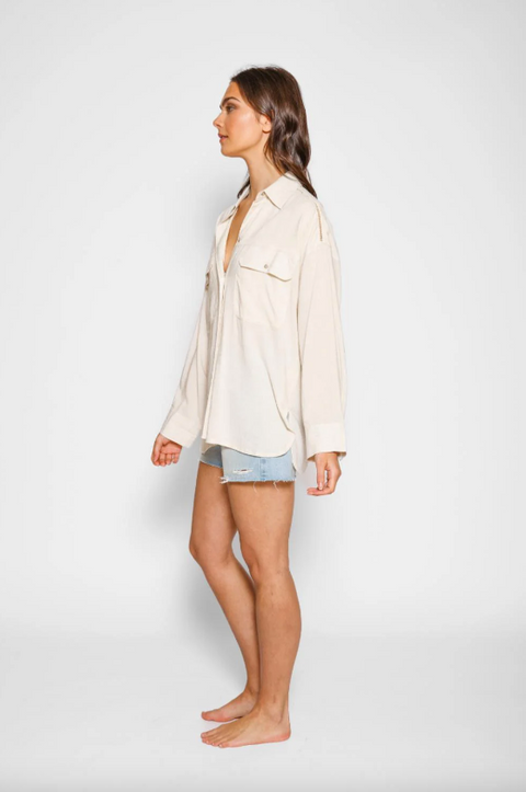 Woman wearing a light-colored shirt and denim shorts on a white background