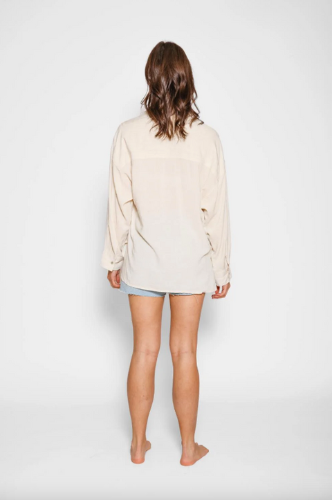 Person wearing a beige cardigan over a light blue shirt on a white background