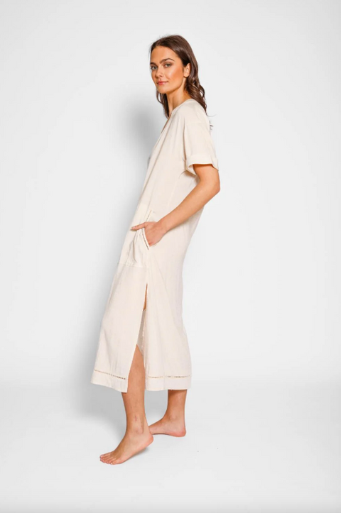 Woman wearing a beige dress with a slit on a white background