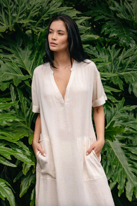 Woman wearing a white dress standing in front of green leafy plants