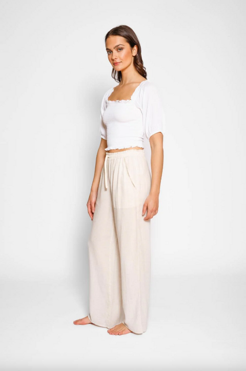 Woman wearing a white top and beige wide-leg pants on a white background