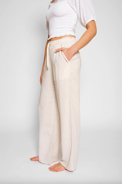 Person wearing a white top and cream-colored wide-leg pants on a plain background