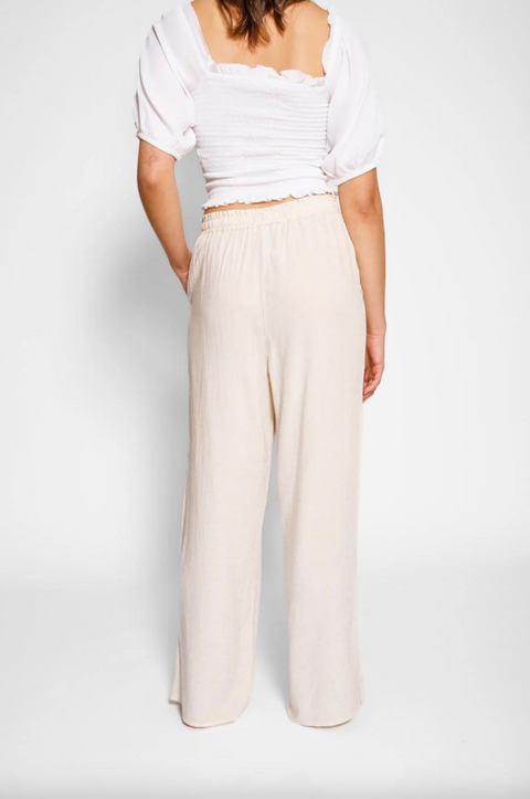 Person wearing a white top and beige wide-leg pants on a plain background