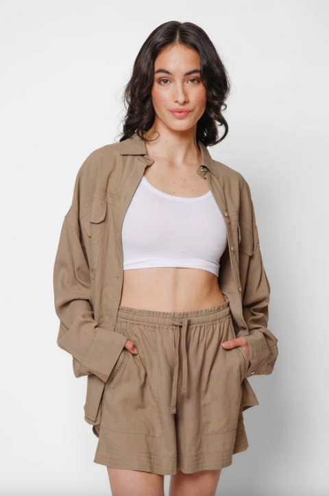 Woman wearing a beige jacket and shorts set with a white top on a light background