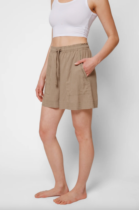 Person wearing a beige skirt and white top on a plain background
