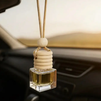 Car air freshener hanging from a car's rearview mirror with a blurred interior background.