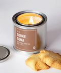Candle in a can labeled 'Cookie Coma' with cookies on a white background