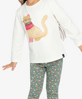 A young girl modeling a white long-sleeve top with a colorful cat graphic and green patterned leggings, standing against a light gray studio background. A small label in the top right reads 'Coton biologique'.