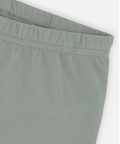 Close-up of a pair of soft sage green pants or shorts showing the elastic waistband and clean fabric texture against a light neutral background.