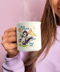 A person in a lavender sweatshirt holds a white ceramic mug with a cartoon skunk illustration and the text 'fuck around find out' against a solid pink background.