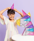 Child playing with colorful geometric building blocks against a purple background