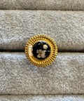 Gold brooch with black center on beige fabric background