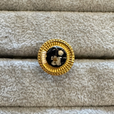 Gold brooch with black center on beige fabric background