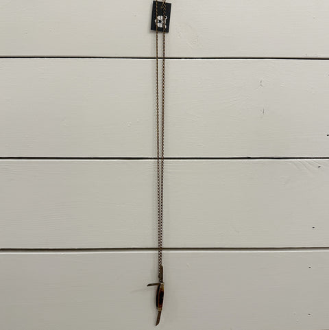 Small metal object with a chain on a white wooden surface