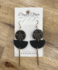 Black and gold earrings on a 'Dayna Olson' card with 'Vancouver Island Handmade' text, on a wooden surface.