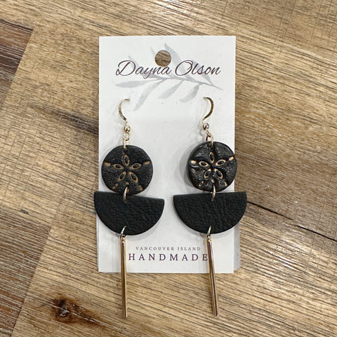 Black and gold earrings on a 'Dayna Olson' card with 'Vancouver Island Handmade' text, on a wooden surface.