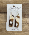 Pair of earrings on a 'Dayna Olson' card with a wooden background